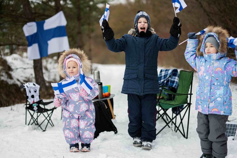 Happy children holding Finnish flag in Lapland during winters