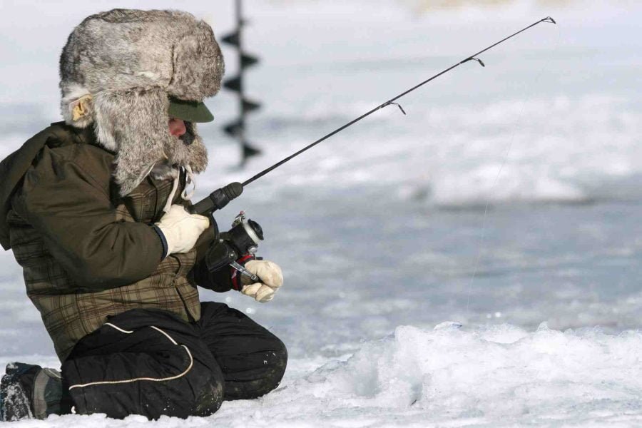 Child enjoying ice fishing during the Ice Fishing with Snowmobile ride in Rovaniemi.