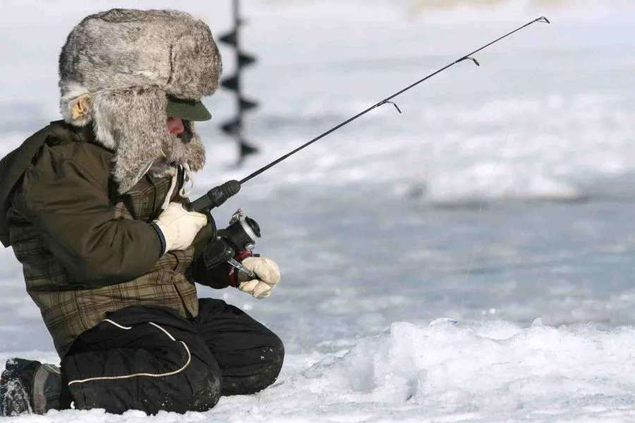 Child enjoying ice fishing during the Ice Fishing with Snowmobile ride in Rovaniemi.