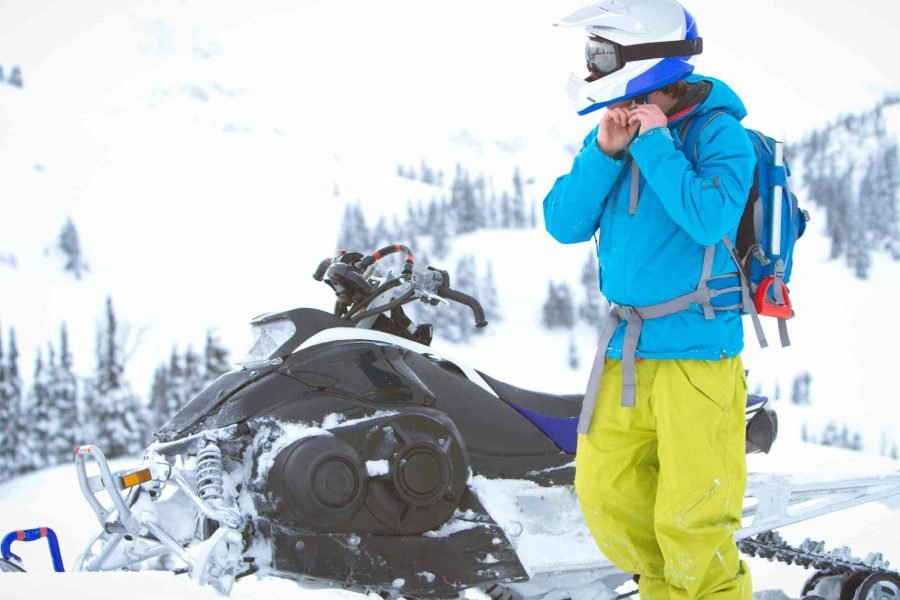 Snowmobile rider adjusting helmet at Snowmobile park in Rovaniemi during full-day snowmobile safari.