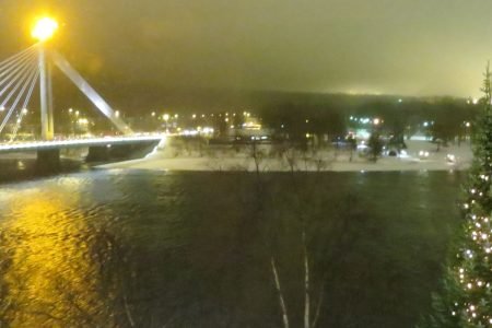 A bridge spanning an iced-over river in Rovaniemi, surrounded by snow-covered trees.