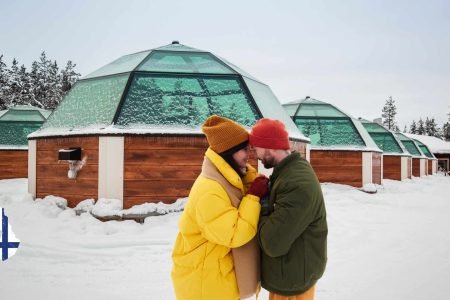 Couple sharing a kiss in front of an igloo resort in Finnish Lapland during March, part of a Finland tour in March.