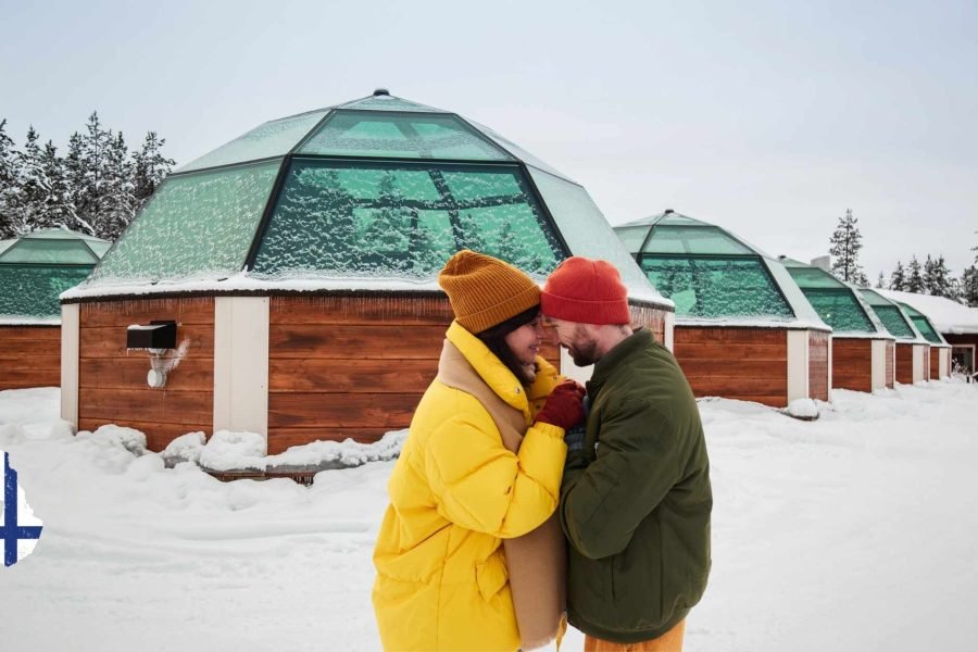 Couple sharing a kiss in front of an igloo resort in Finnish Lapland during March, part of a Finland tour in March.