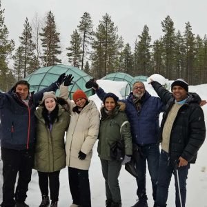 Tourists posing in front of glass igloos at Kakslauttanen Arctic Resort, Saariselkä, showcasing the beauty of an igloo stay in Finland.