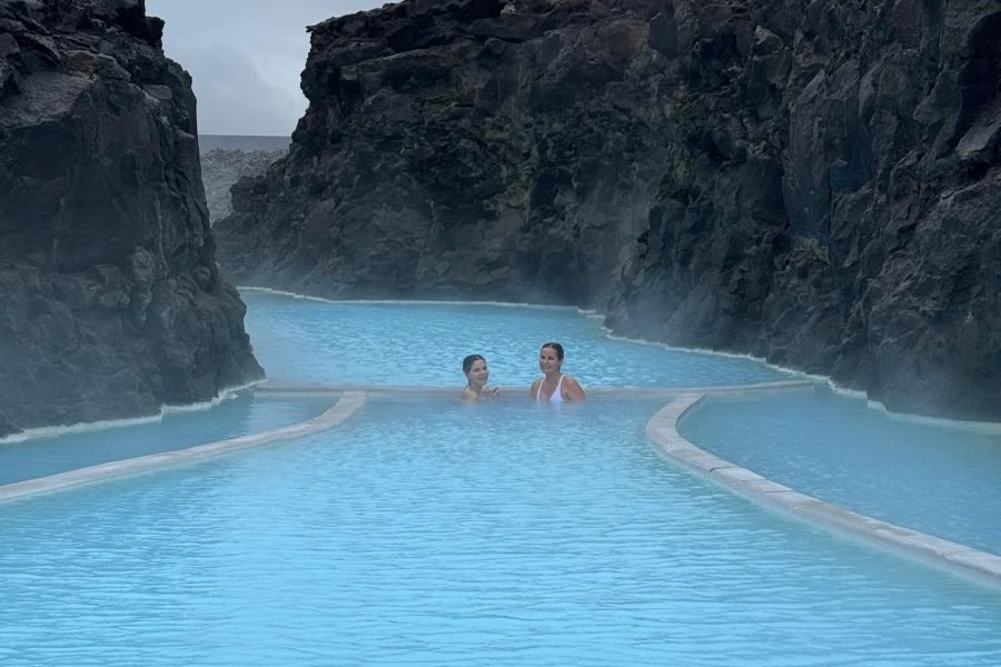 Two female travelers smiling and posing in the geothermal waters of Blue Lagoon, Iceland.