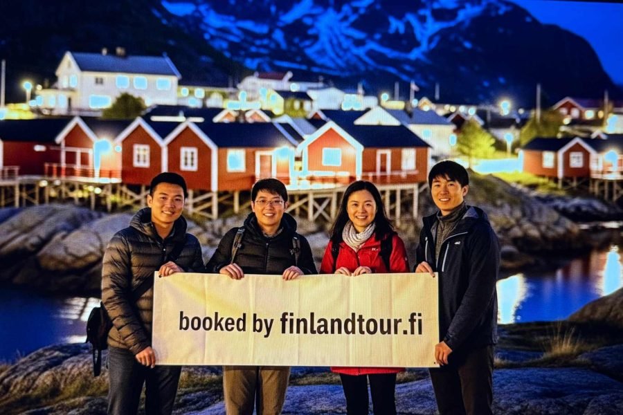 Finlandtour.fi’s guests smiling and posing in front of iconic red houses in Lofoten during the best Finland and Norway tour with Arctic train in Narvik