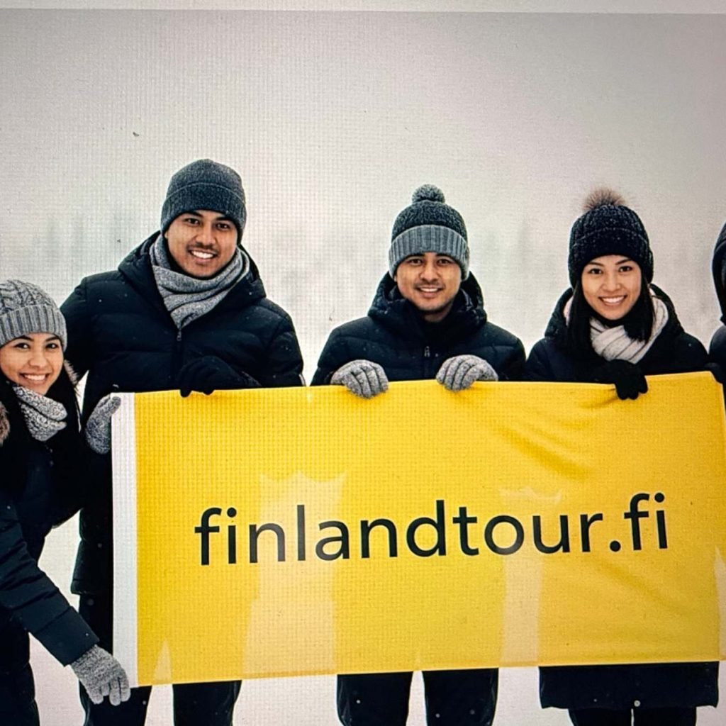 Group of happy travelers at Husky Park in Rovaniemi during their 10 days Finland tour from Singapore.
