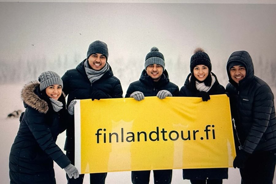 Group of happy travelers at Husky Park in Rovaniemi during their 10 days Finland tour from Singapore.
