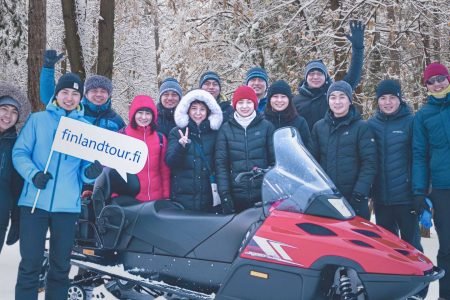 Travelers from Hong Kong posing after a thrilling snowmobile safari during their 15 days Finland tour from Hong Kong