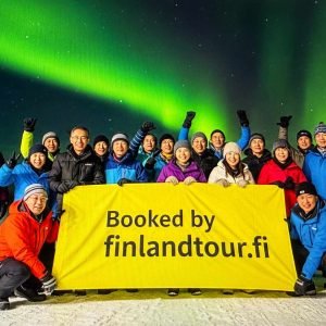 Travelers from Singapore posing in Finland under the magical northern lights during their 12 days Finland tour from Singapore.