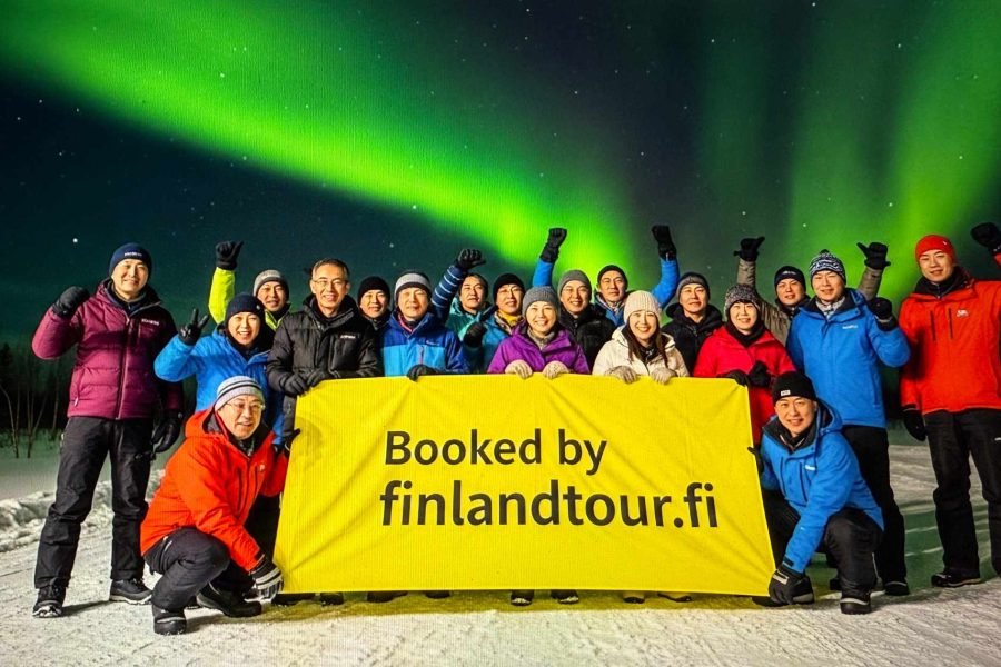 Travelers from Singapore posing in Finland under the magical northern lights during their 12 days Finland tour from Singapore.