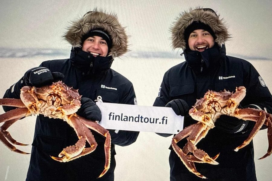 Travelers smiling and holding freshly caught King crabs during the Kirkenes King Crab Safari on the Best Finland and Norway tour with Northern Lights Arctic Cruise