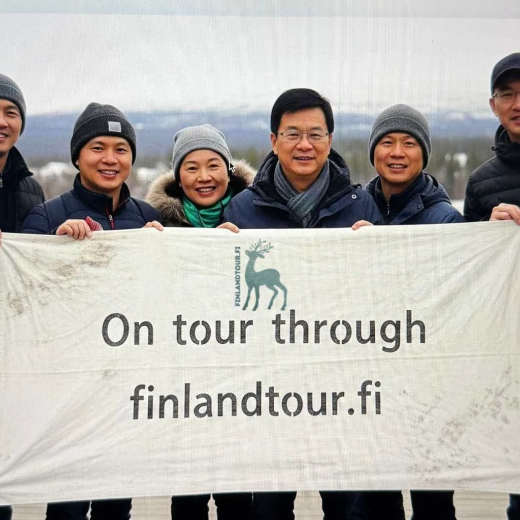 Travelers in Rovaniemi, Finland, posing with a finlandtour.fi banner during their 13 days Finland tour from Singapore.