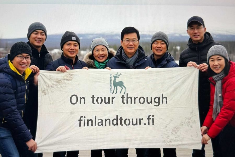 Travelers in Rovaniemi, Finland, posing with a finlandtour.fi banner during their 13 days Finland tour from Singapore.